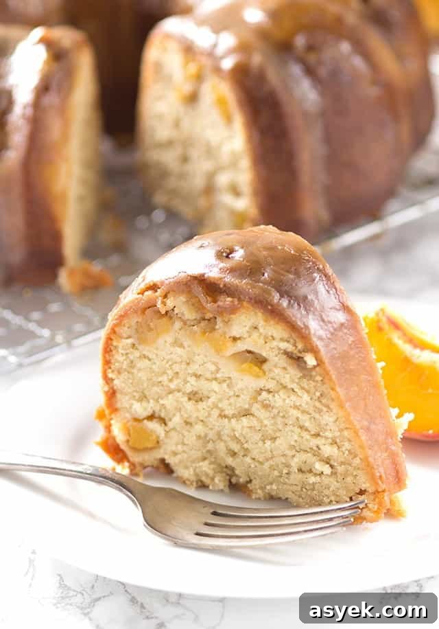 A luscious slice of homemade pound cake made with juicy peaches, delicately arranged on a plate.