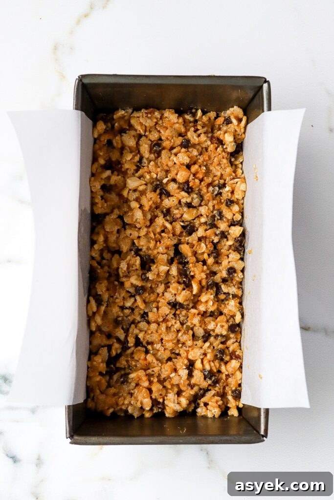 chocolate peanut butter rice krispie bars pressed into a parchment lined loaf pan