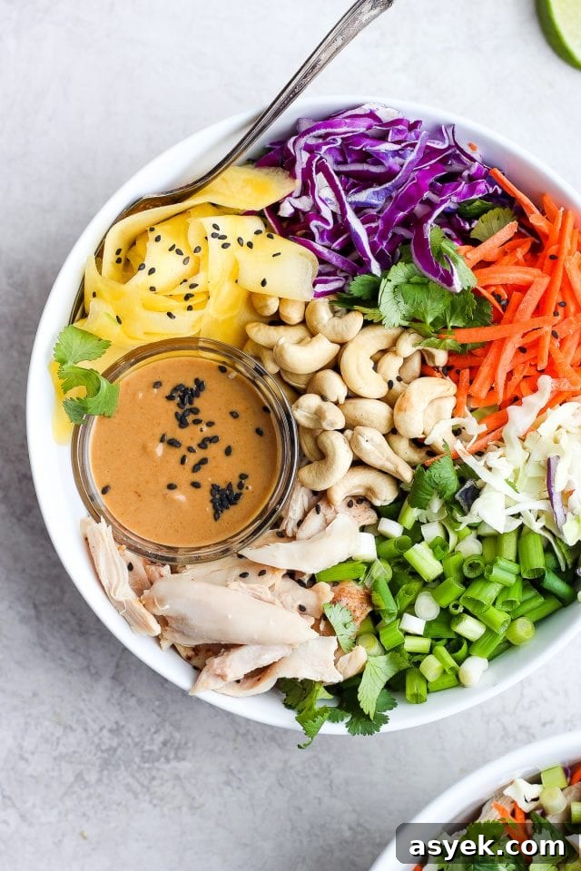 A chopped rotisserie chicken salad in a white bowl with a small dish of dressing.