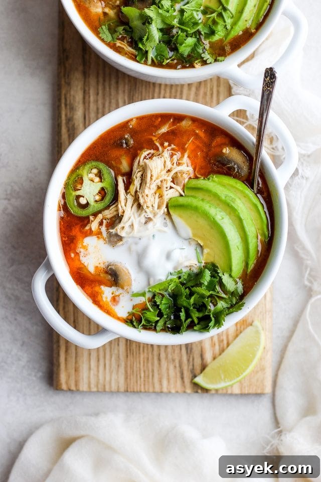 Slow cooker white chicken chili in a white bowl with a spoon sticking out the side.