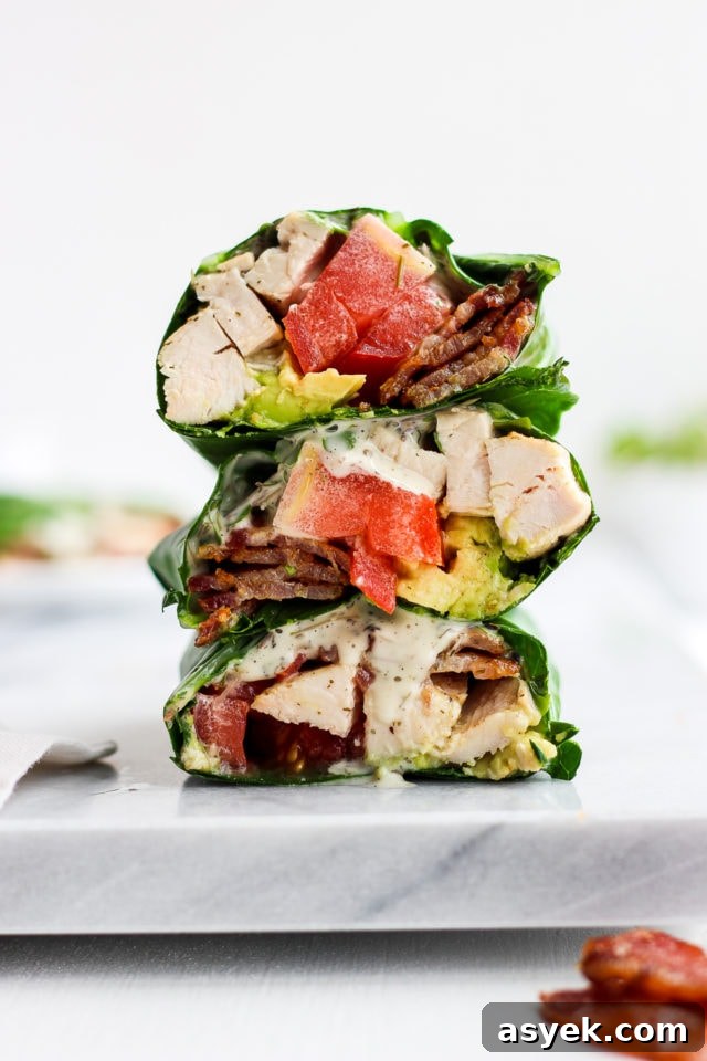 A chicken bacon club collard green wrap cut in half and stacked on top of each other.