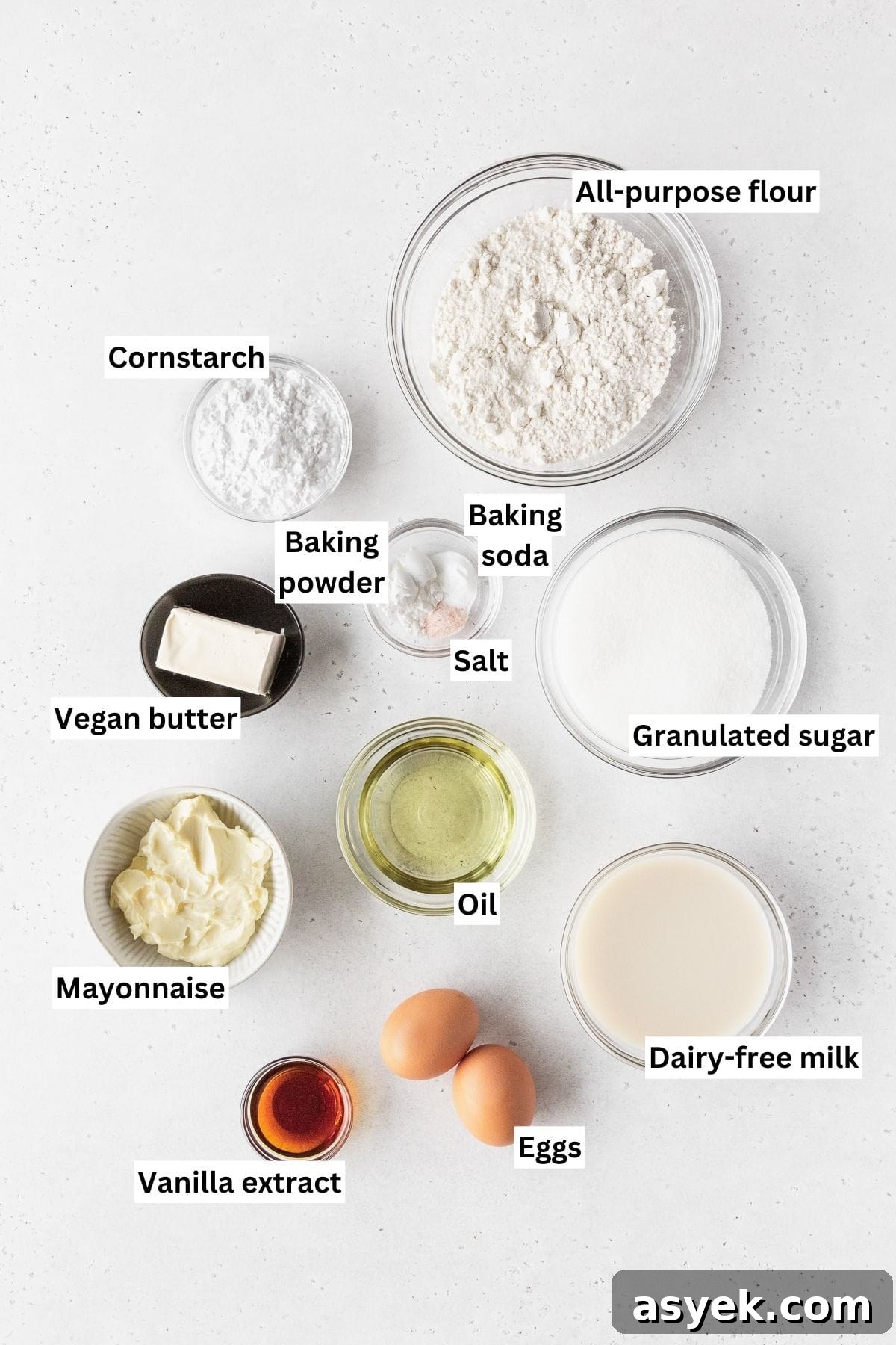 Ingredients for making dairy-free vanilla cupcakes laid out on a white table.