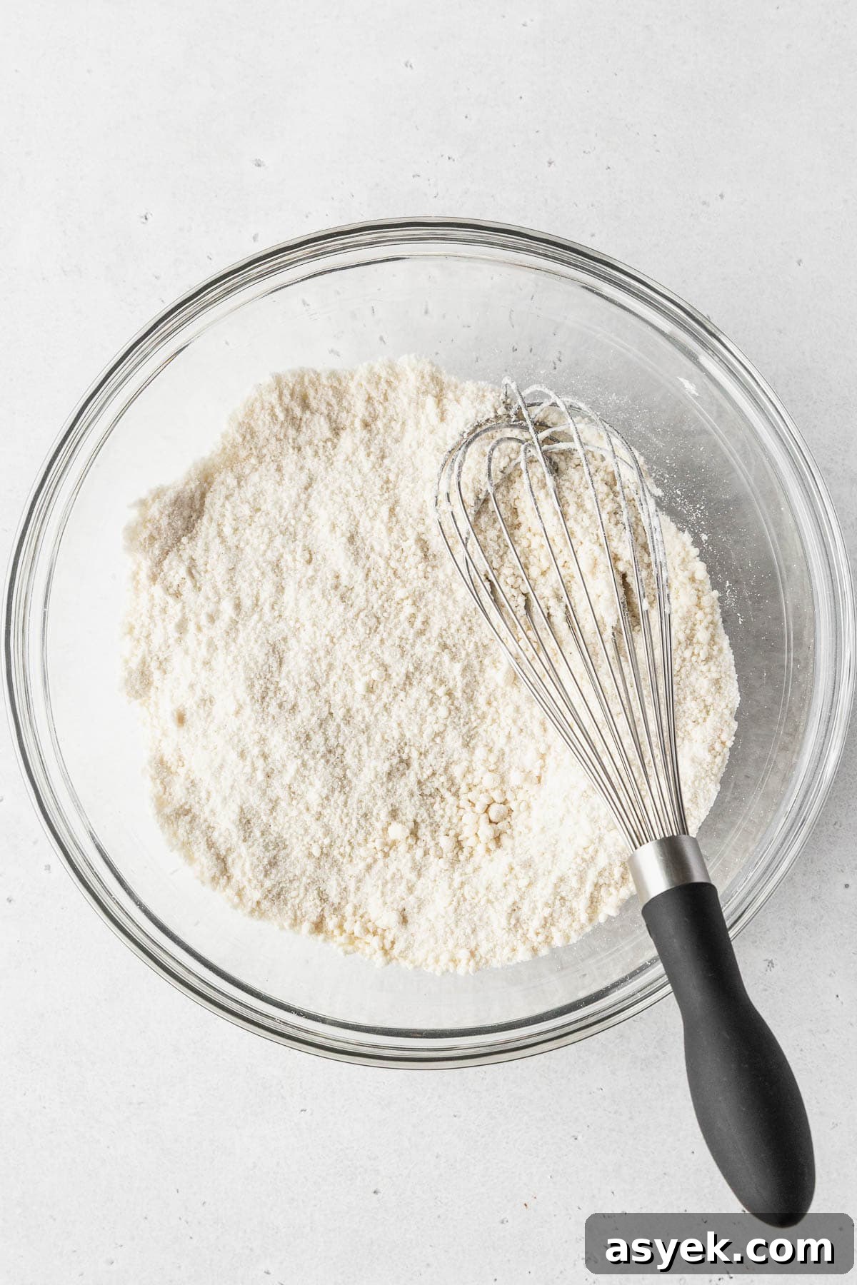 Dry ingredients whisked together in a clear glass mixing bowl.