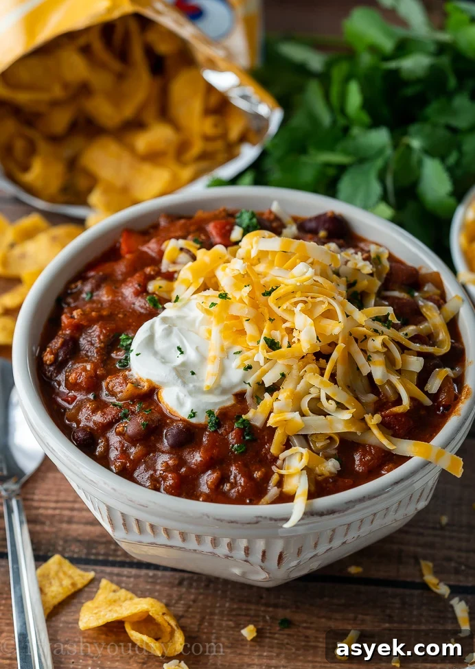 Homemade Chili Recipe from Scratch - Authentic Chili Con Carne 6 thick and hearty chili in white bowl with sour cream and shredded cheese on top.