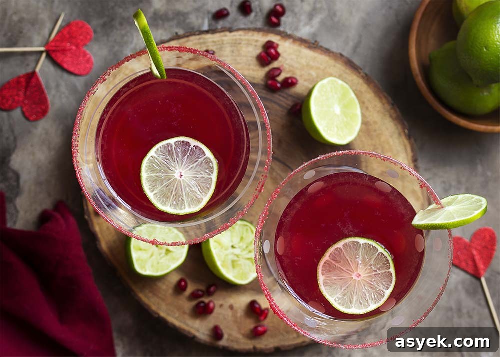 Pomegranate Vodka Martini Recipe: Classic Cocktail 6 Top view of two pomegranate cocktails each garnished with lime and rimmed with red sugar.