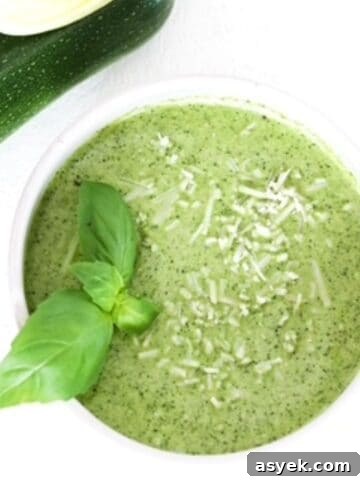 Zucchini pesto in a white bowl topped with fresh basil leaves.