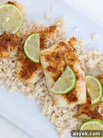 Air-fried cod topped with seasoning and slices of fresh lime on a white dish.