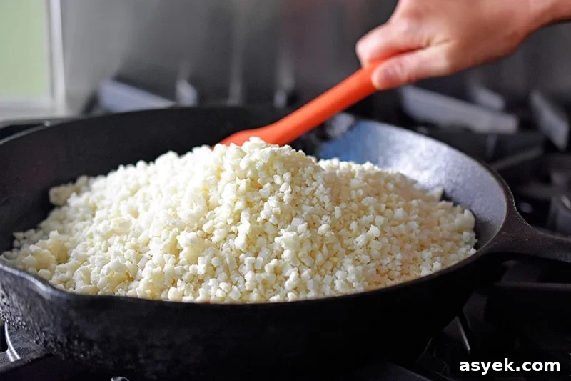 Whole30 Cauliflower Rice Recipes for Every Meal 4 A large cast iron skillet filled with riced cauliflower.