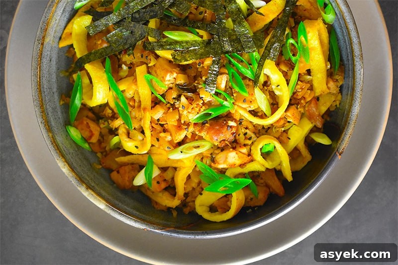 Whole30 Cauliflower Rice Recipes for Every Meal 10 An overhead shot of a bowl of Kimchi Cauliflower Fried Rice topped with toasted seaweed slices and scallions.