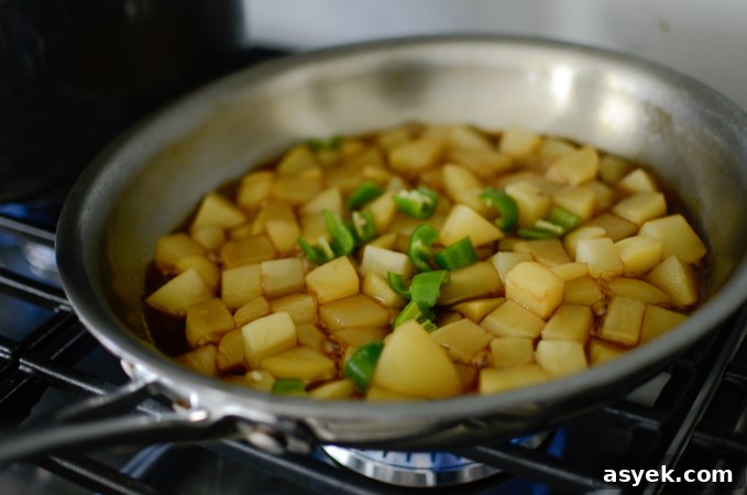 Korean Braised Potatoes (Gamja Jorim) Recipe 6 Slices of green chili are added to simmering potato in a skillet.