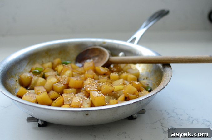 Korean Braised Potatoes (Gamja Jorim) Recipe 8 Korean braised potatoes are garnished with sesame seeds in a skillet.