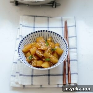 Cubes of Korean potato side dish is on a napkin with a pair of chopsticks