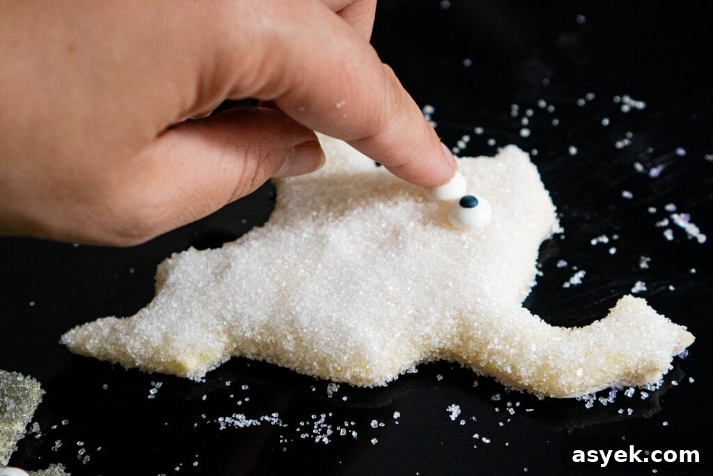 Placing edible eyes onto a ghost sugar bread cut out by hand