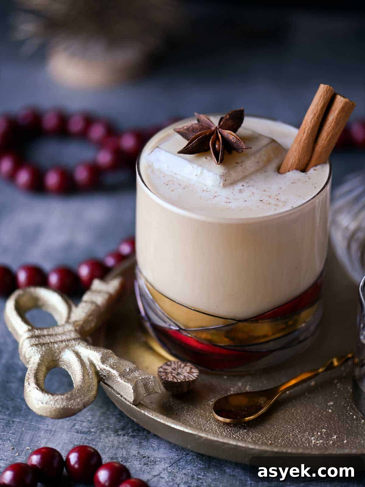 Festive Eggnog White Russian Cocktail Recipe 2 Close-up of a white Russian cocktail with star anise and cinnamon stick on top.