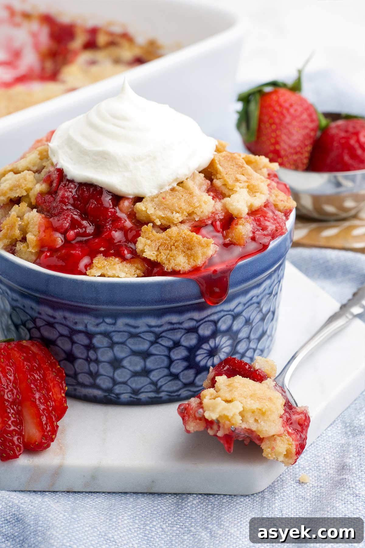 Strawberry dump cake served in a small dish with whipped cream.