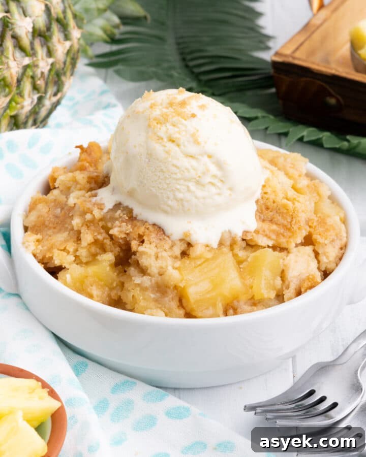 Pineapple dump cake in a white bowl with a scoop of ice cream.