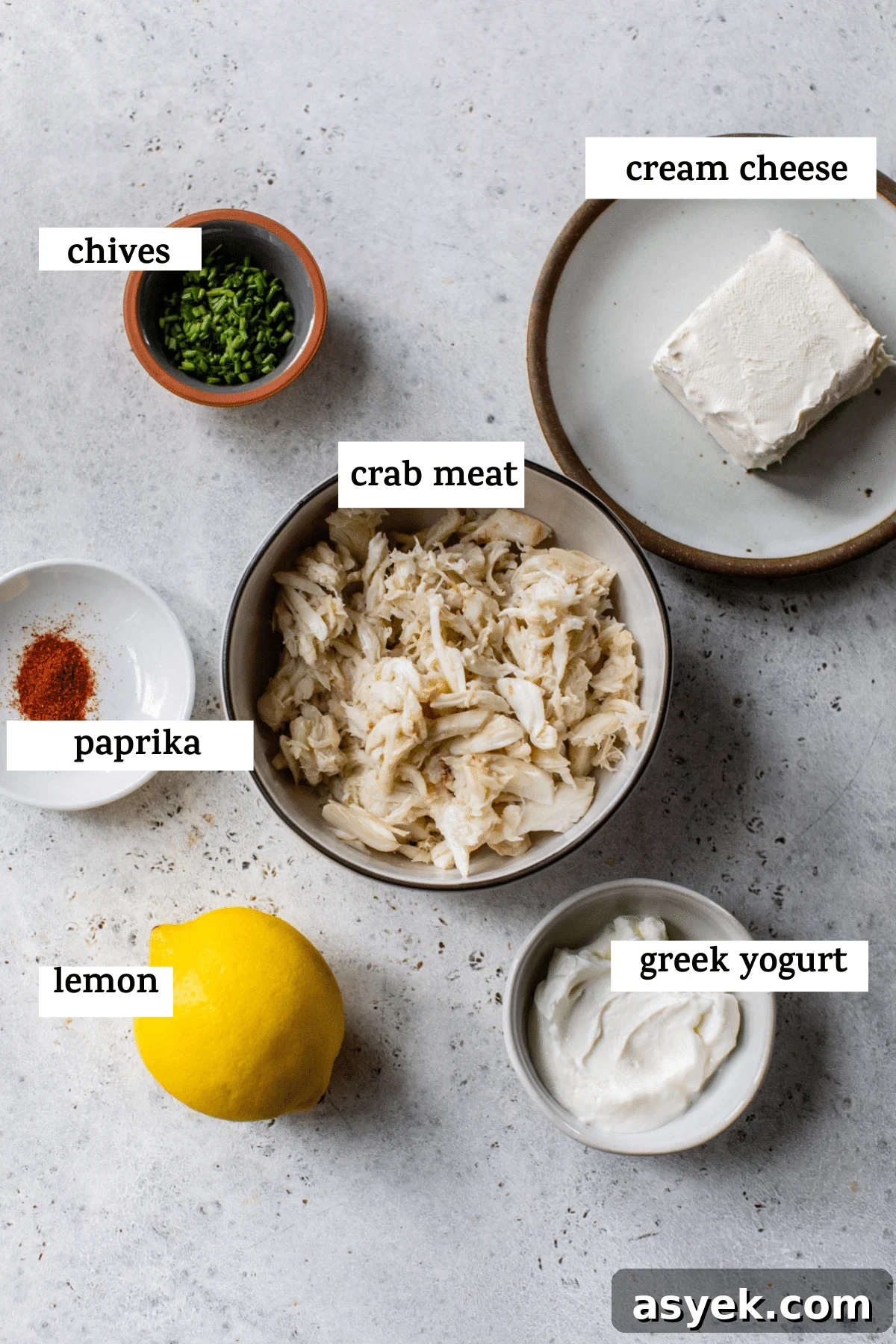 Creamy Chilled Crab Dip Recipe with Lemon and Dill 3 all ingredients on a table; chives, cream cheese, paprika, crab meat, lemon, and greek yogurt