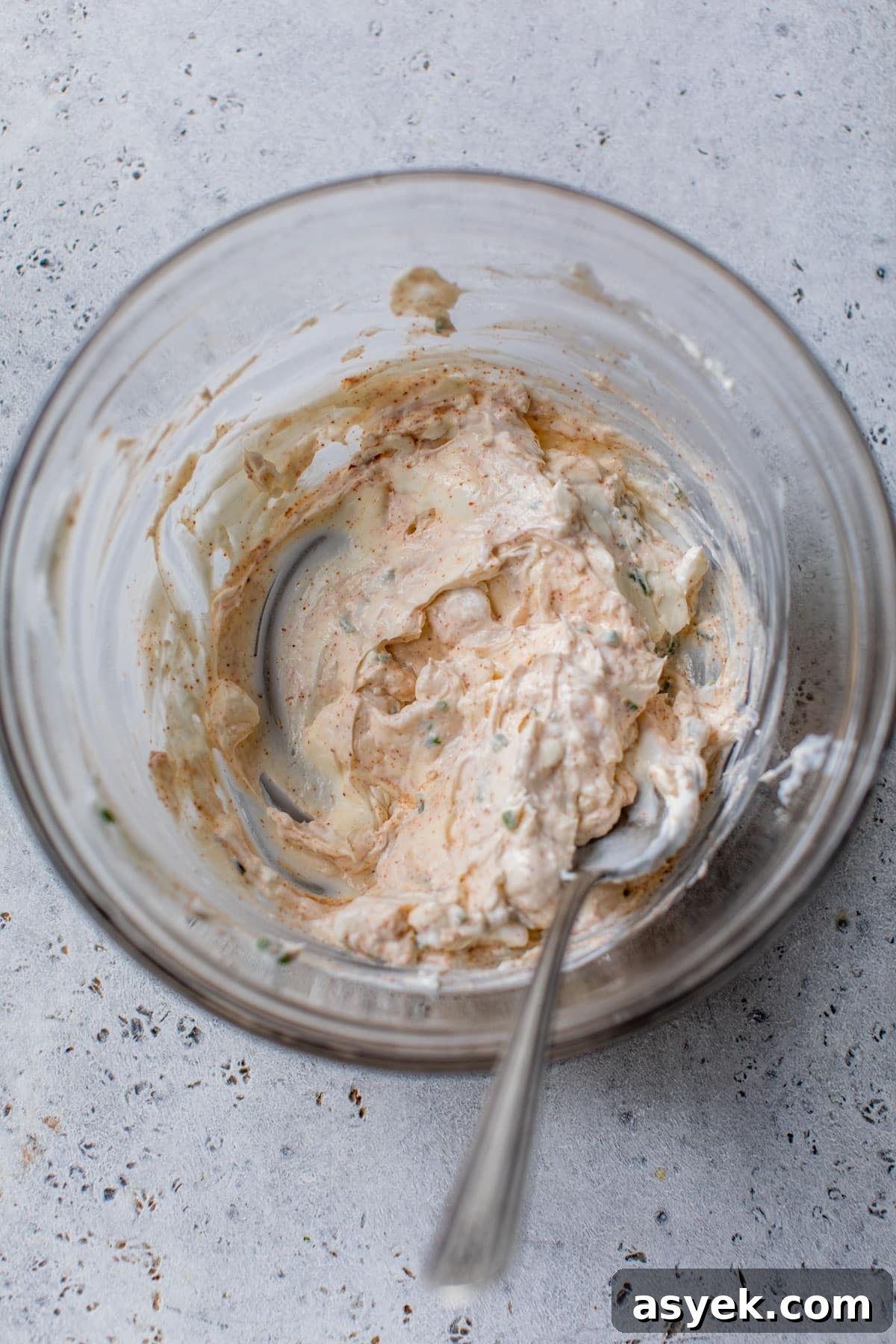 Creamy Chilled Crab Dip Recipe with Lemon and Dill 4 cream cheese, greek yogurt and spices mixed together in a glass bowl with a spoon