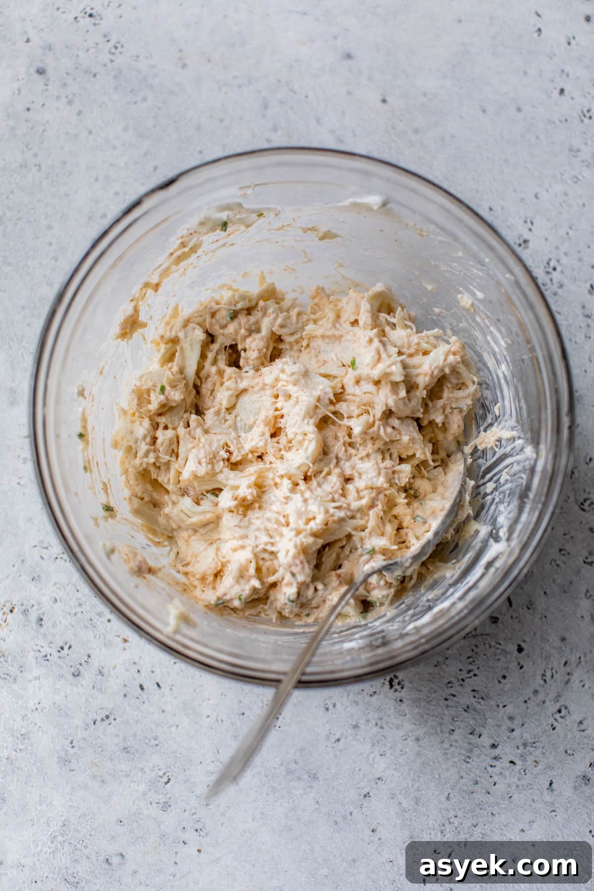 Creamy Chilled Crab Dip Recipe with Lemon and Dill 5 crab meat added to the greek yogurt mixture in a glass bowl with a spoon