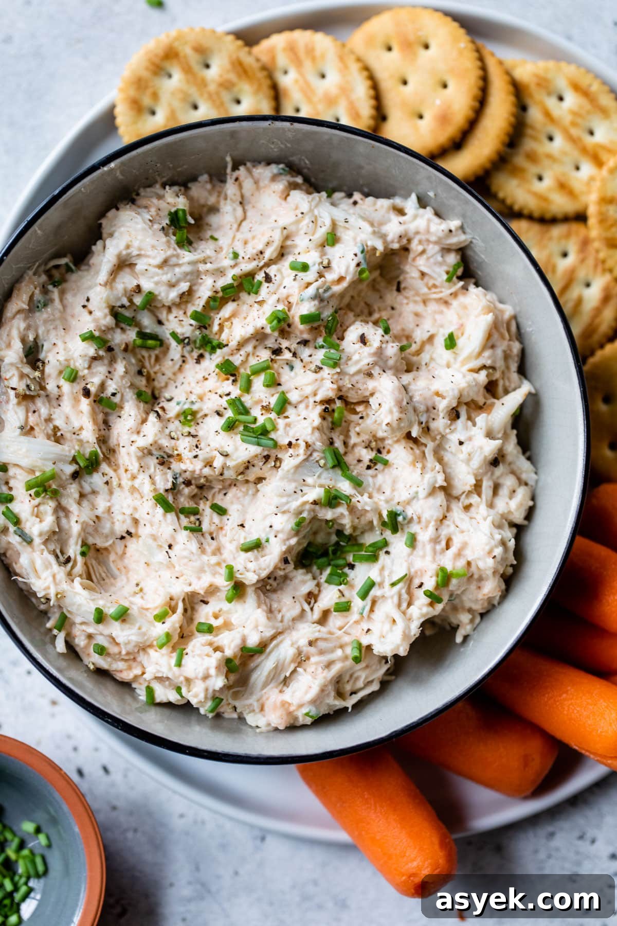 Creamy Chilled Crab Dip Recipe with Lemon and Dill 6 cold crab dip in a bowl with chives on top and on a plate with crackers and carrots