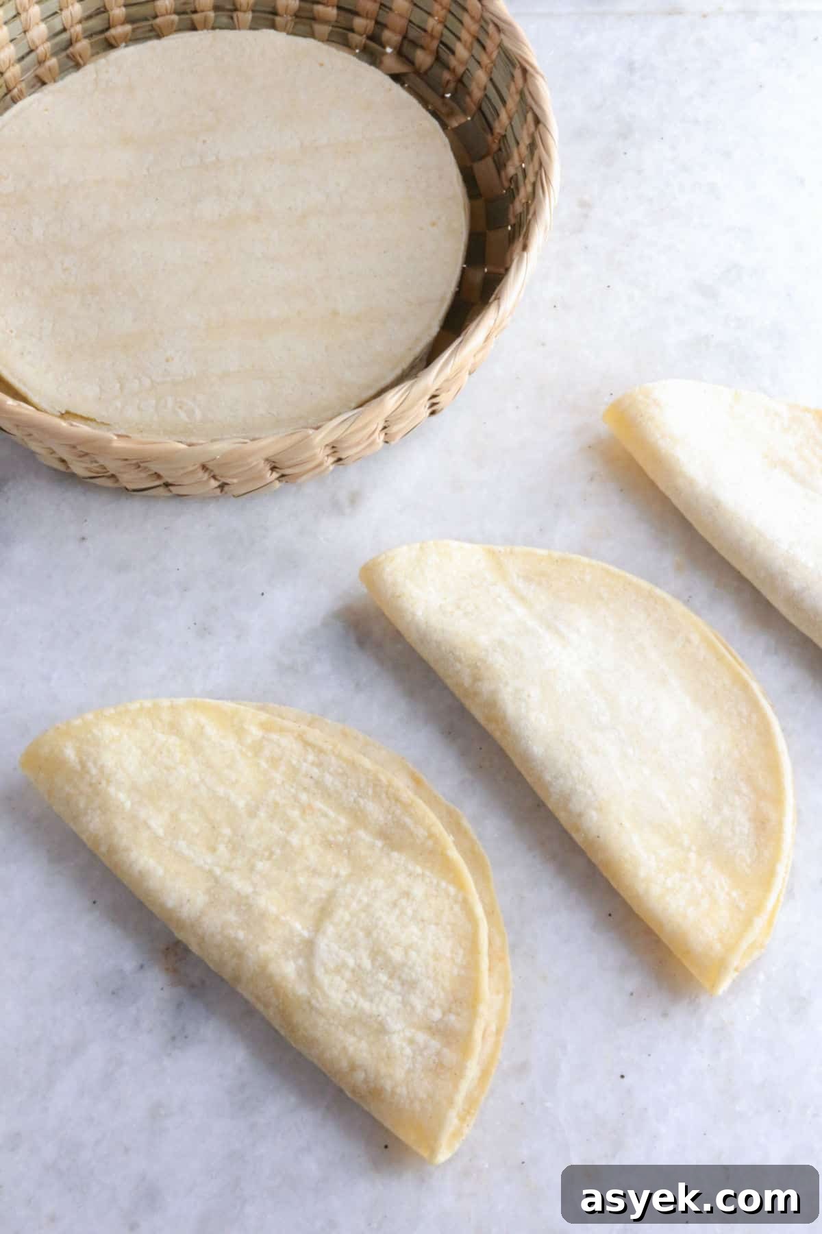 Crispy Mexican Bean Taco Recipe (Tacos Dorados) 6 Folded bean tacos ready to be fried, with a basket with corn tortillas behind them