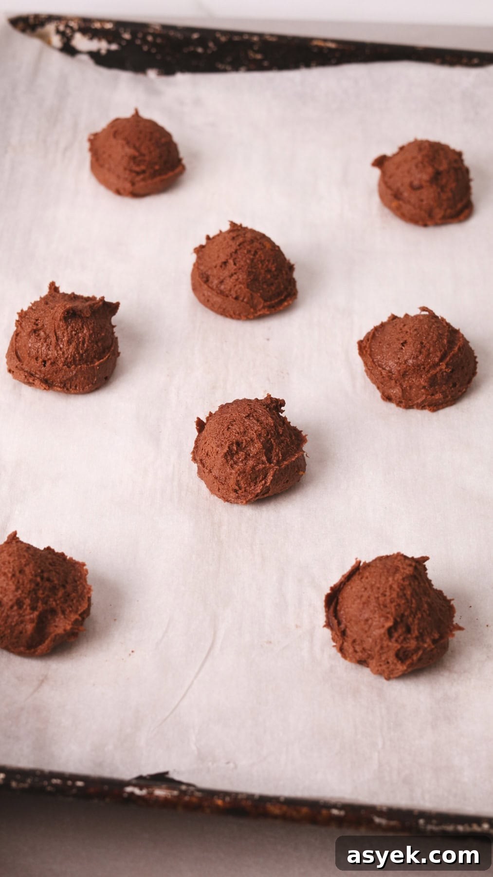 Chocolate and orange cookie dough on a parchment lined baking sheet.
