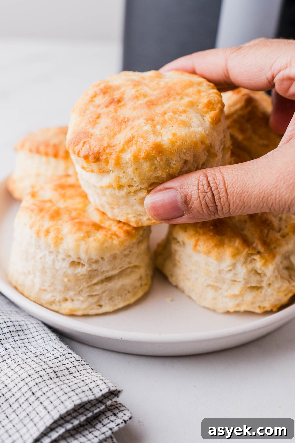 Buttery Air Fryer Biscuits in 15 Minutes 14 picking an air fryer biscuit from the plate.