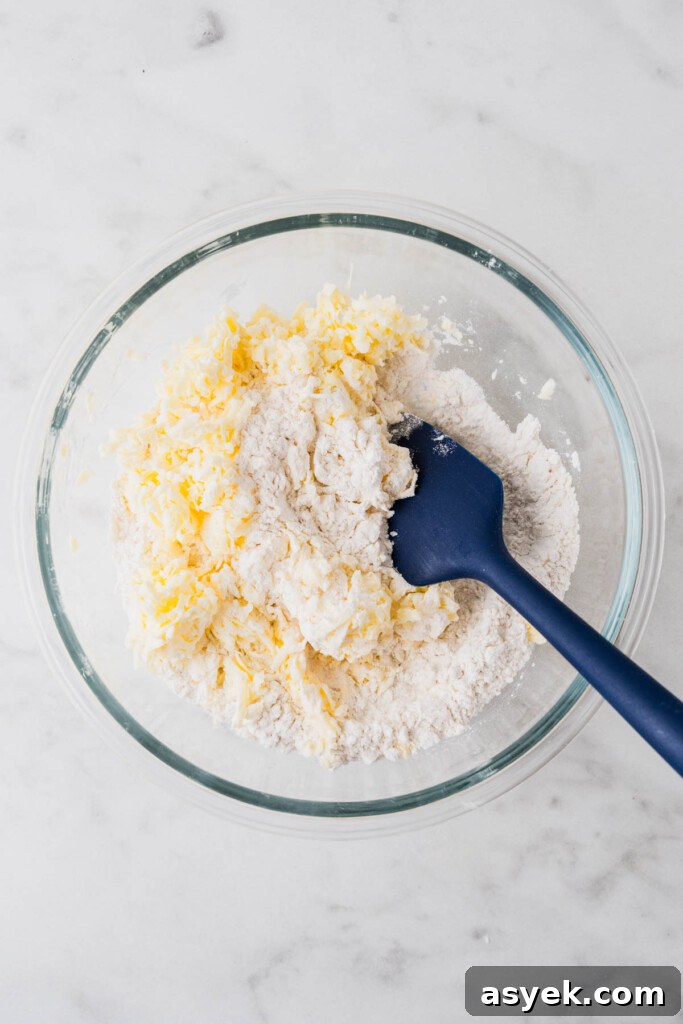 Buttery Air Fryer Biscuits in 15 Minutes 6 grated butter and flour in a bowl with a blue mixing spoon.