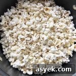 Horizontal image of a pot filled with white puffy kernels.