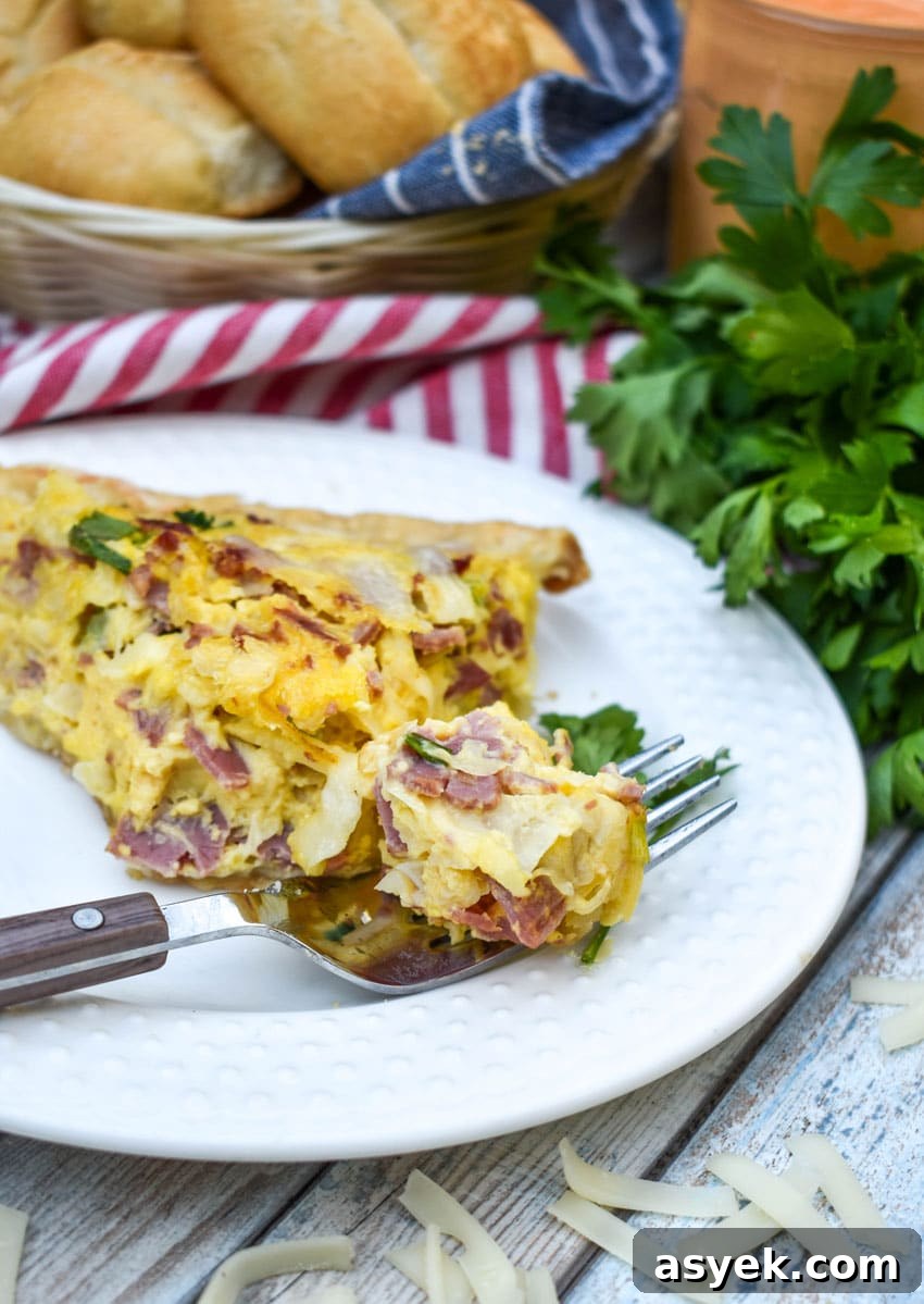Reuben Quiche Recipe: Corned Beef, Swiss and Sauerkraut 7 a fork holding a bite of reuben quiche resting on a the edge of a small white plate