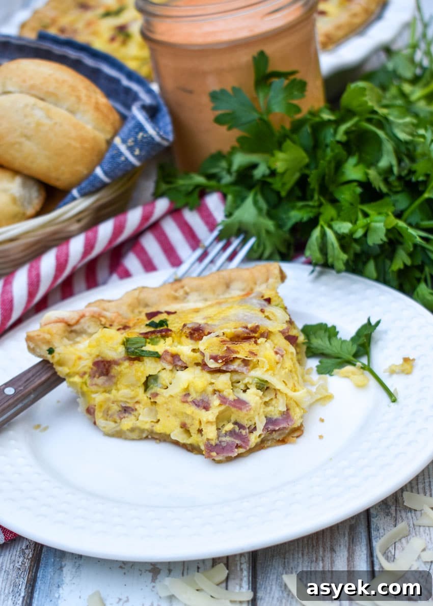 Reuben Quiche Recipe: Corned Beef, Swiss and Sauerkraut 8 a slice of a baked reuben quiche on a small white plate with a fork resting on the side