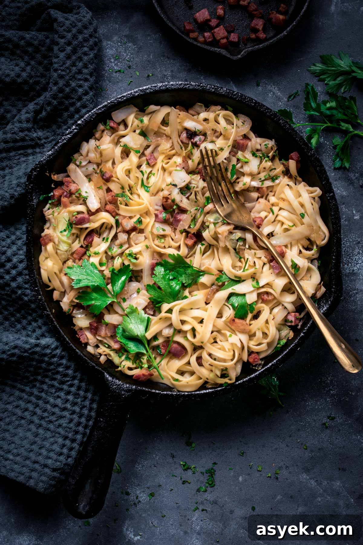 Fried cabbage and noodles with crispy bacon in a skillet.