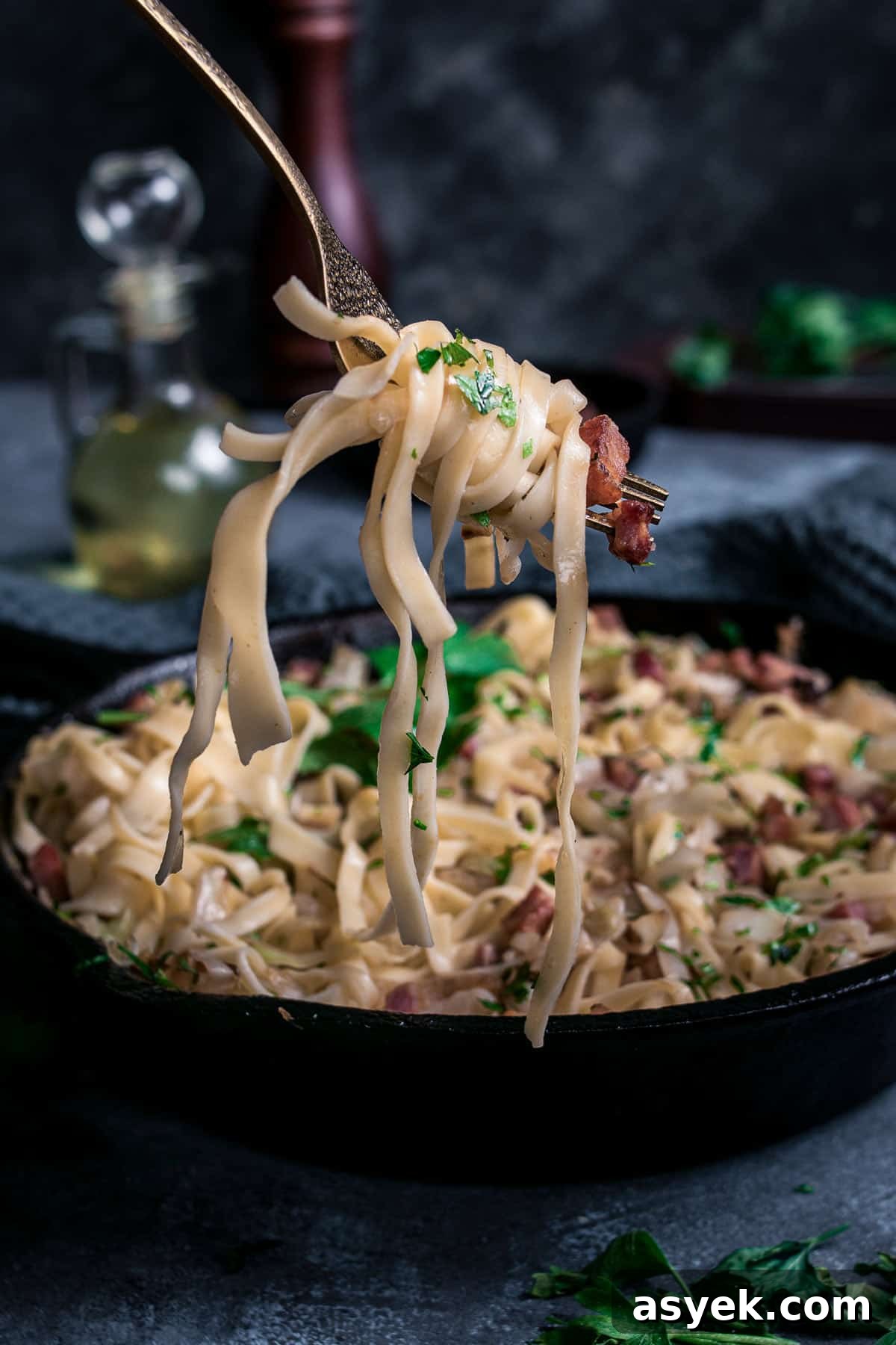 Noodles with fried cabbage and bacon wrapped around a fork.