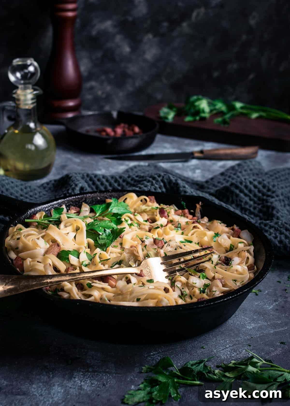 A skillet with haluski sprinkled with fresh parsley on a table with fork.