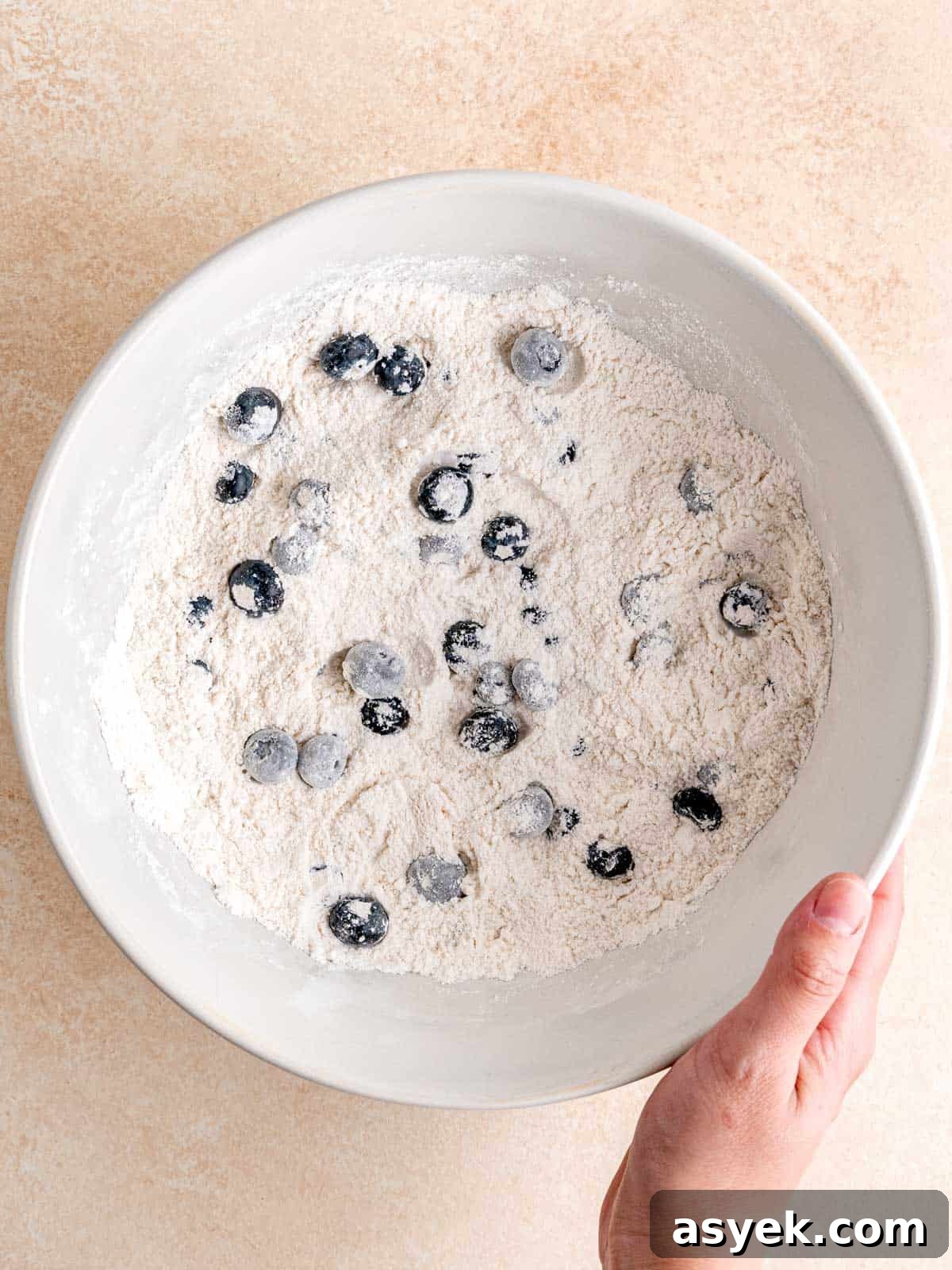 Tossing blueberries into a flour mixture.