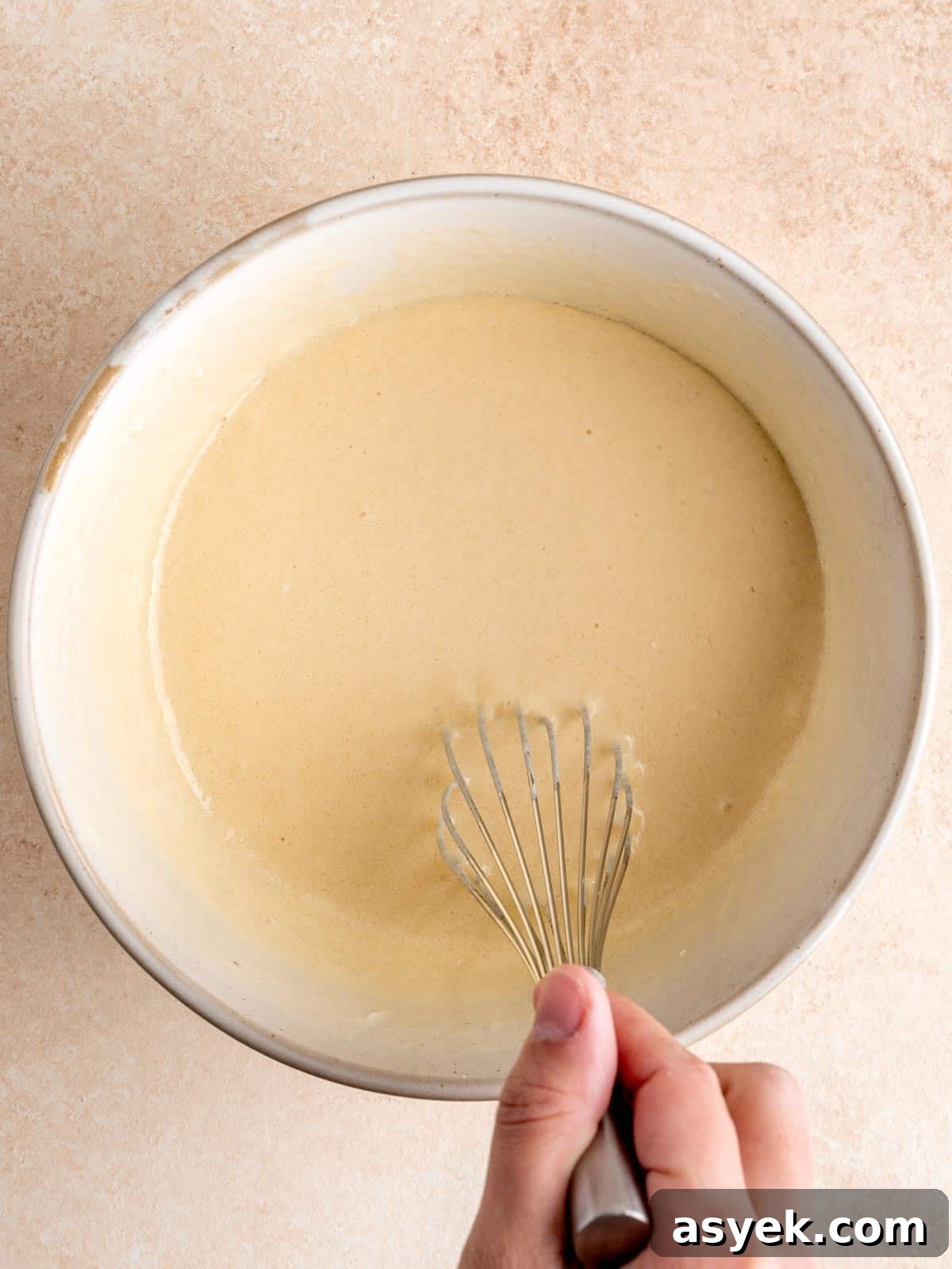 Whisking eggs, vegetable oil, vanilla extract, sour cream, milk and sourdough discard in a bowl.