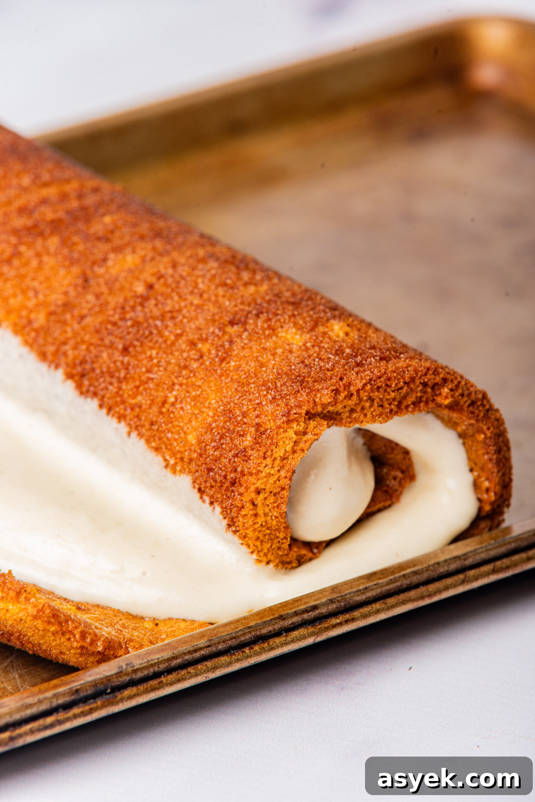 Roll cake being rolled up with the cream cheese filling, ready to be served.