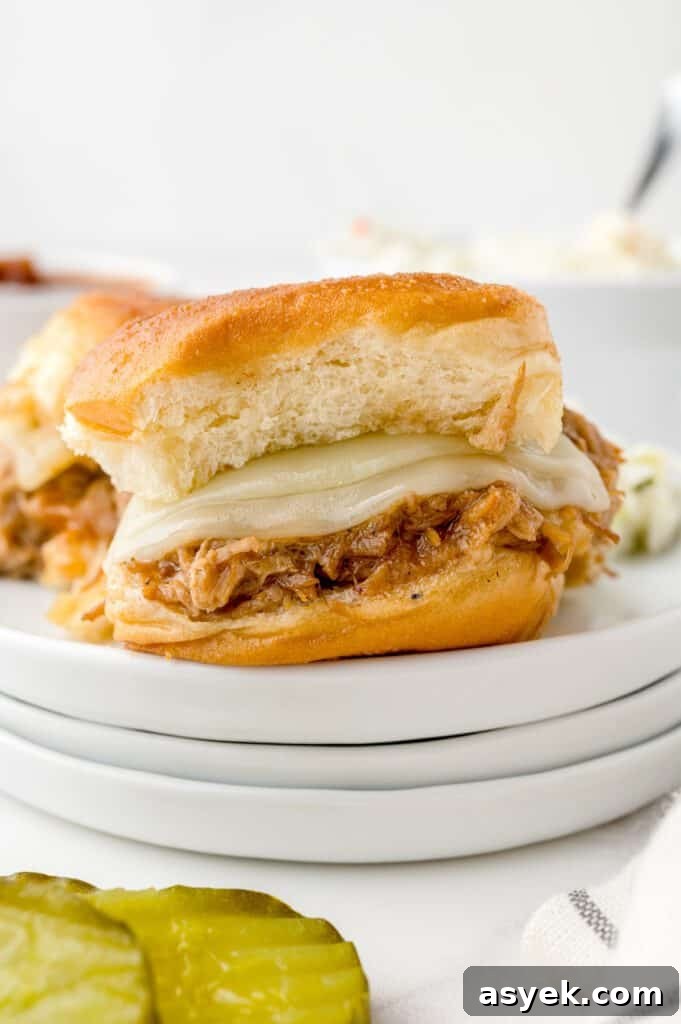 BBQ Pulled Pork Sliders on Hawaiian Rolls Recipe 2 Pulled pork slider on a plate with pickles and coleslaw.