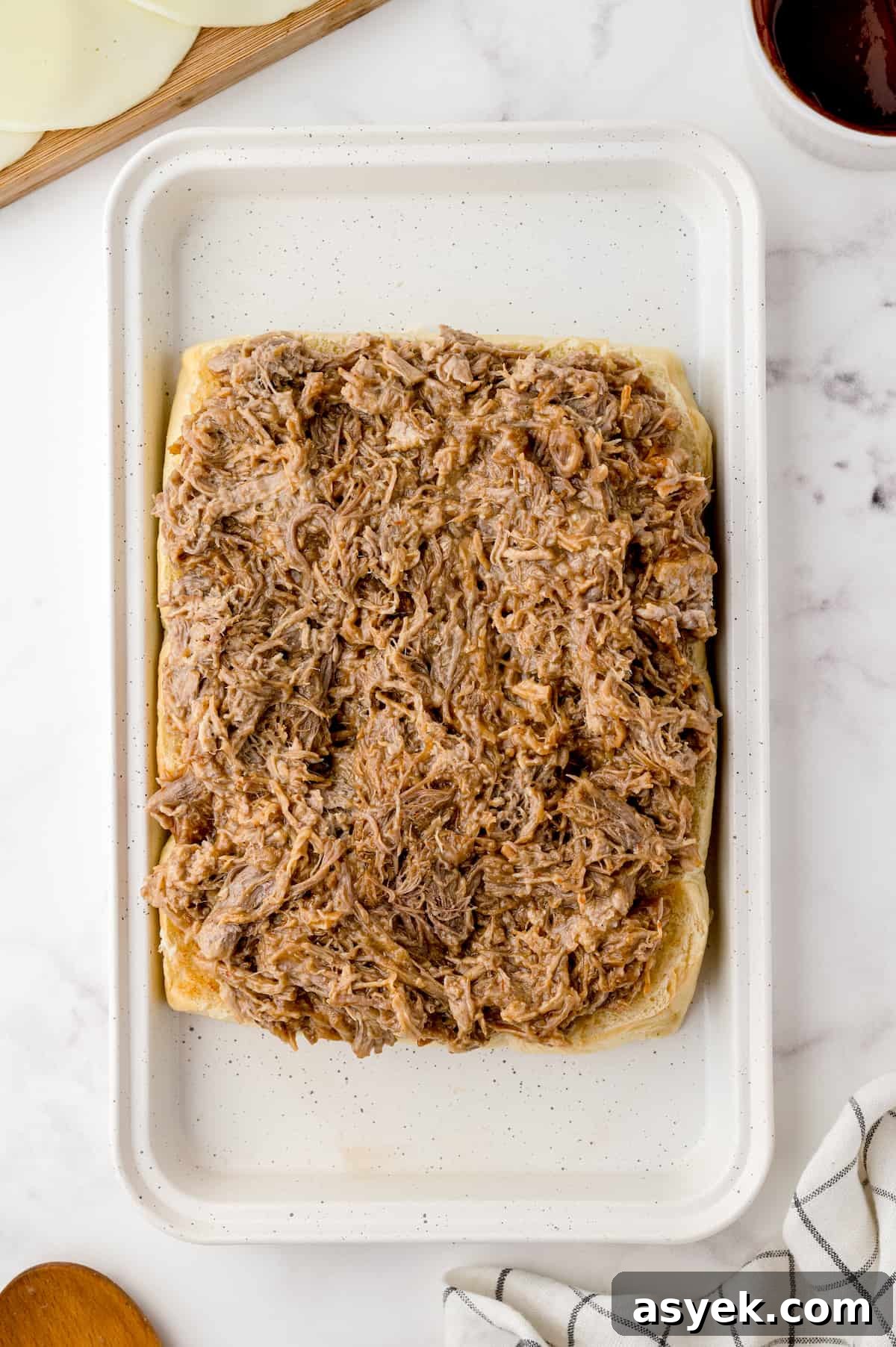 BBQ Pulled Pork Sliders on Hawaiian Rolls Recipe 6 Pulled pork spread on slider buns on a rimmed baking sheet