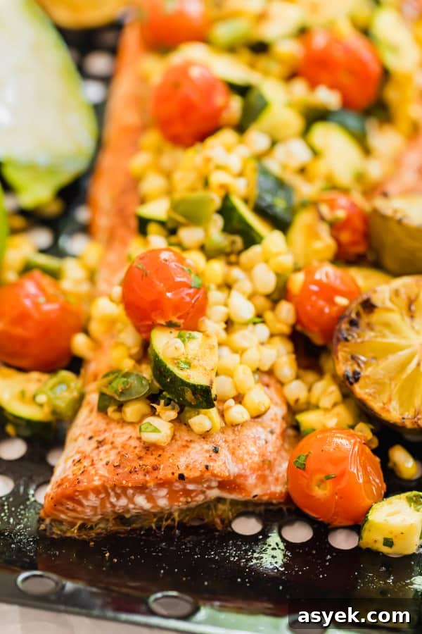 A close-up of the side of the salmon with grilled vegetables on top.
