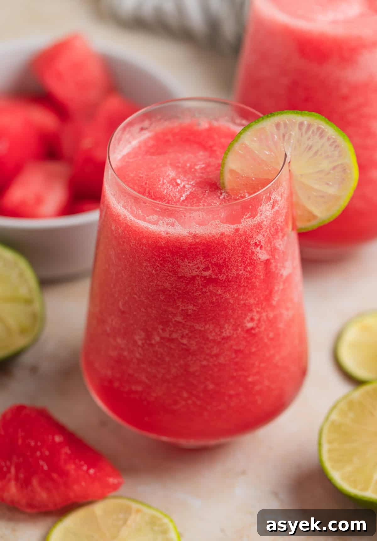 Glass with watermelon frosé and lime slice to garnish.