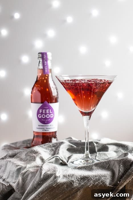 Sparkling Pomegranate Popper Cocktail Recipe 3 A cocktail glass of Pomegranate Popper Cocktail beside a bottle of Feel Good Cranberry and Pomegranate juice