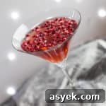 Sparkling Pomegranate Popper Cocktail Recipe 6 cocktail glass with pomegranate popper cocktail and pomegranate seeds against a sparkly grey background
