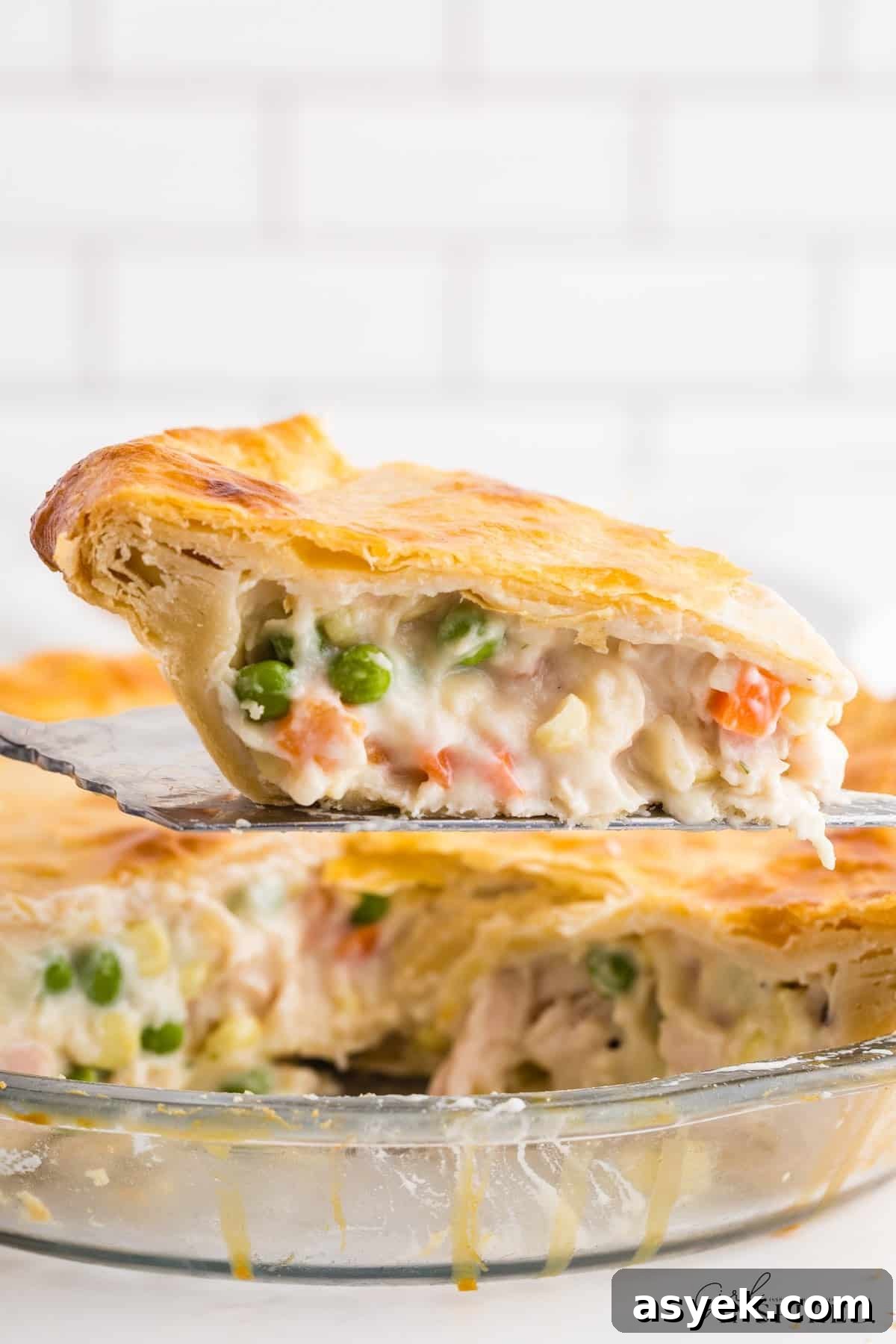 Scooping a slice of creamy chicken pot pie from the pie plate.
