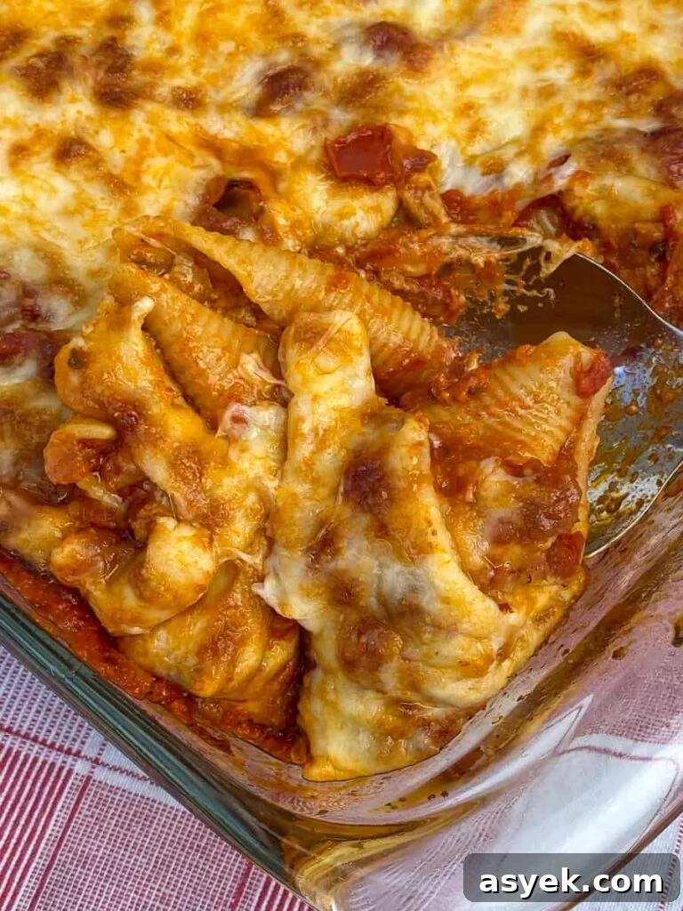 Serving spoon of cheese covered stuffed pasta shells with ground beef