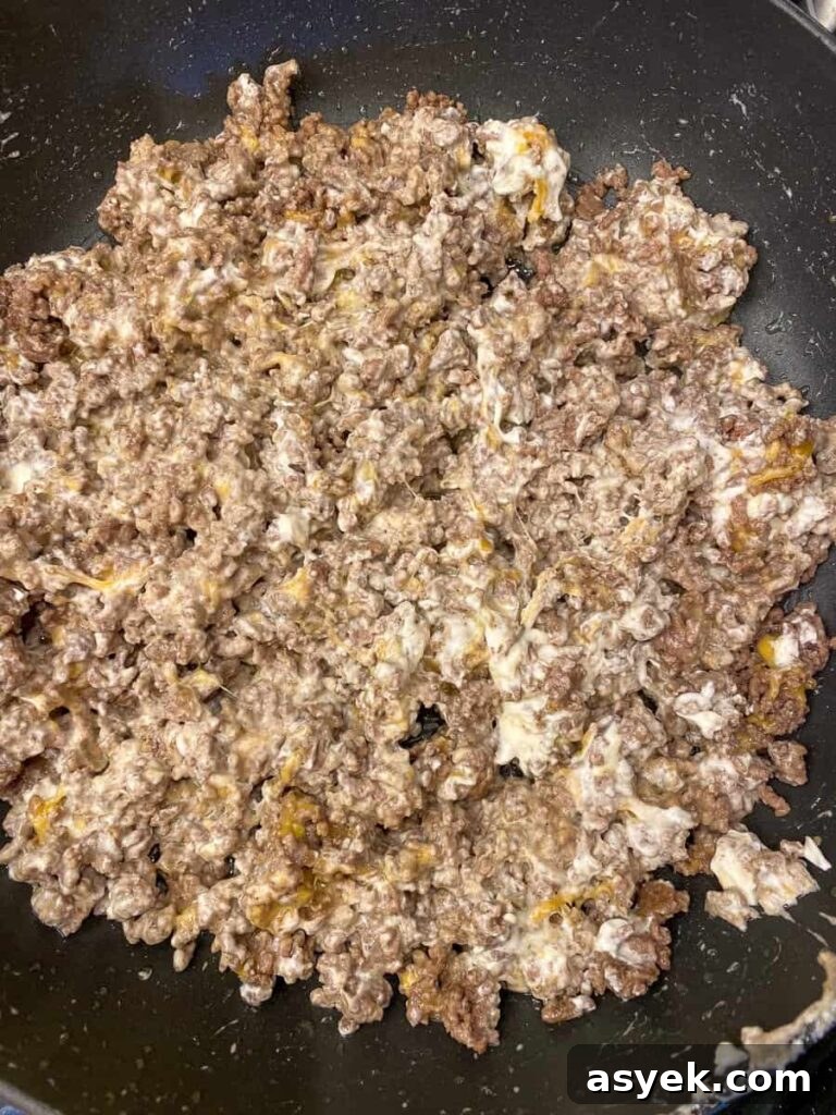 Cream cheese mixed into cooked ground beef in a skillet