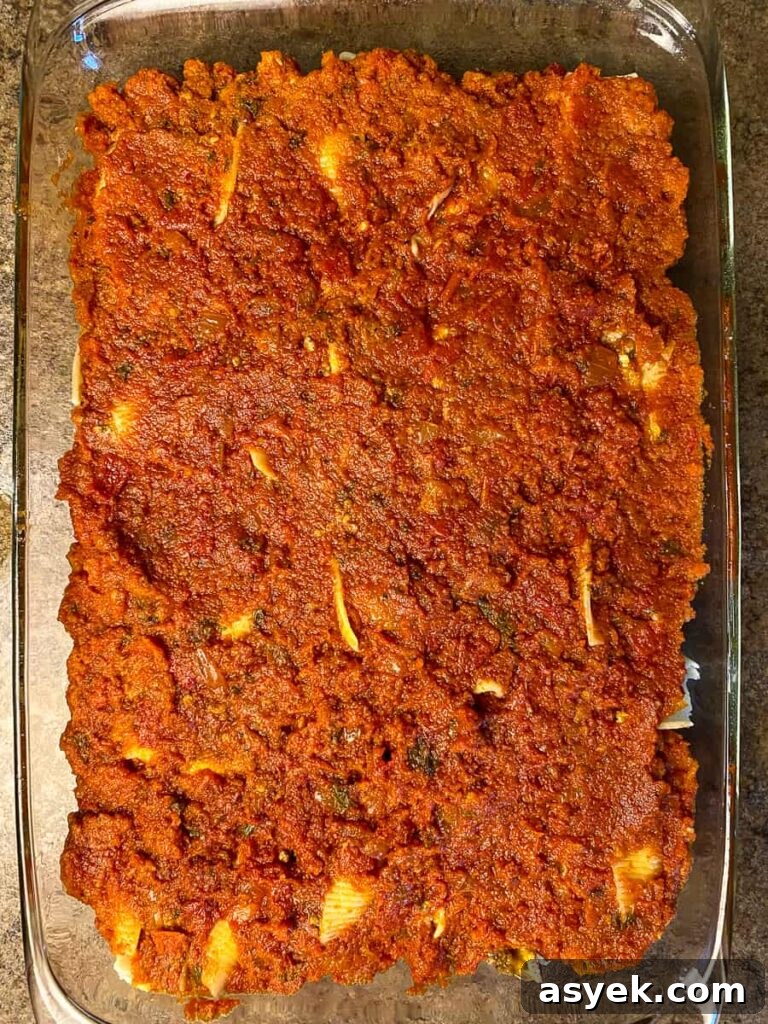 Red pasta sauce spread over stuffed shells before baking