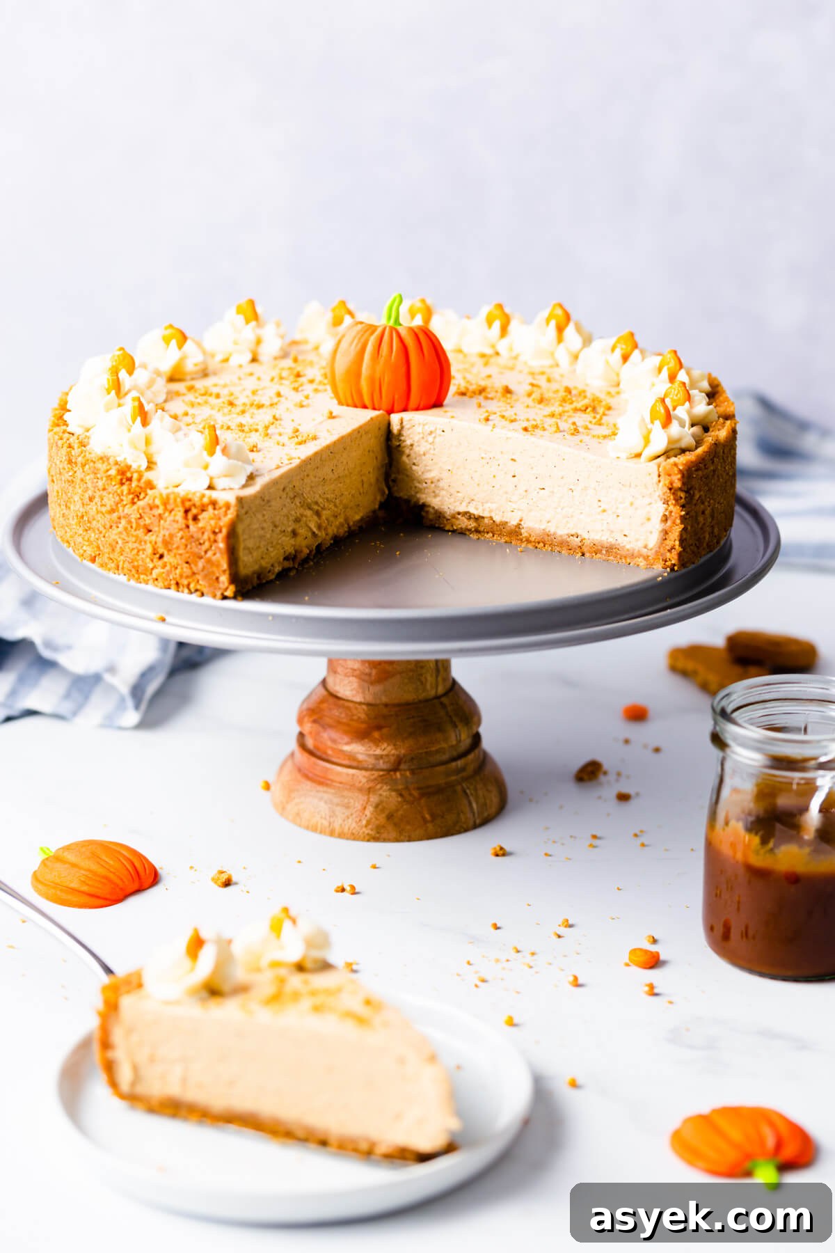 Creamy No-Bake Pumpkin Cheesecake Recipe 2 straight ahead angle of a no bake pumpkin cheesecake on a small cake stand with couple of pieces cut out