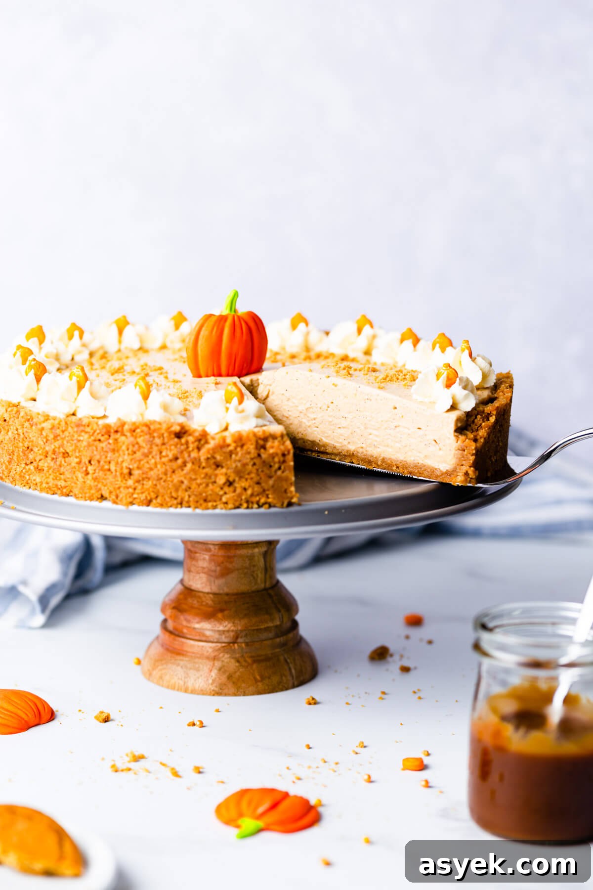 Creamy No-Bake Pumpkin Cheesecake Recipe 12 side angle close up at a slice of pumpkin cheesecake being lifted on a cake lifter