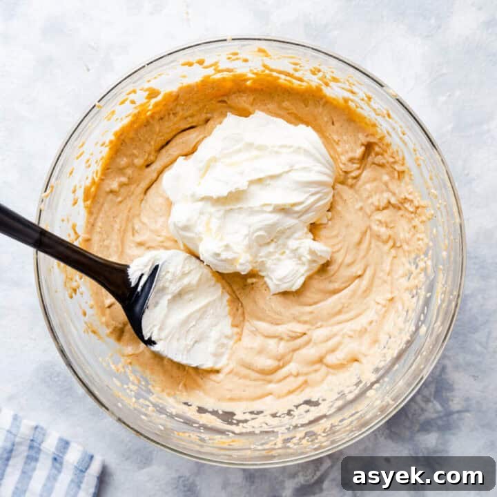 Creamy No-Bake Pumpkin Cheesecake Recipe 8 overhead shot of a bowl with the whipped cream being added to the cheesecake filling